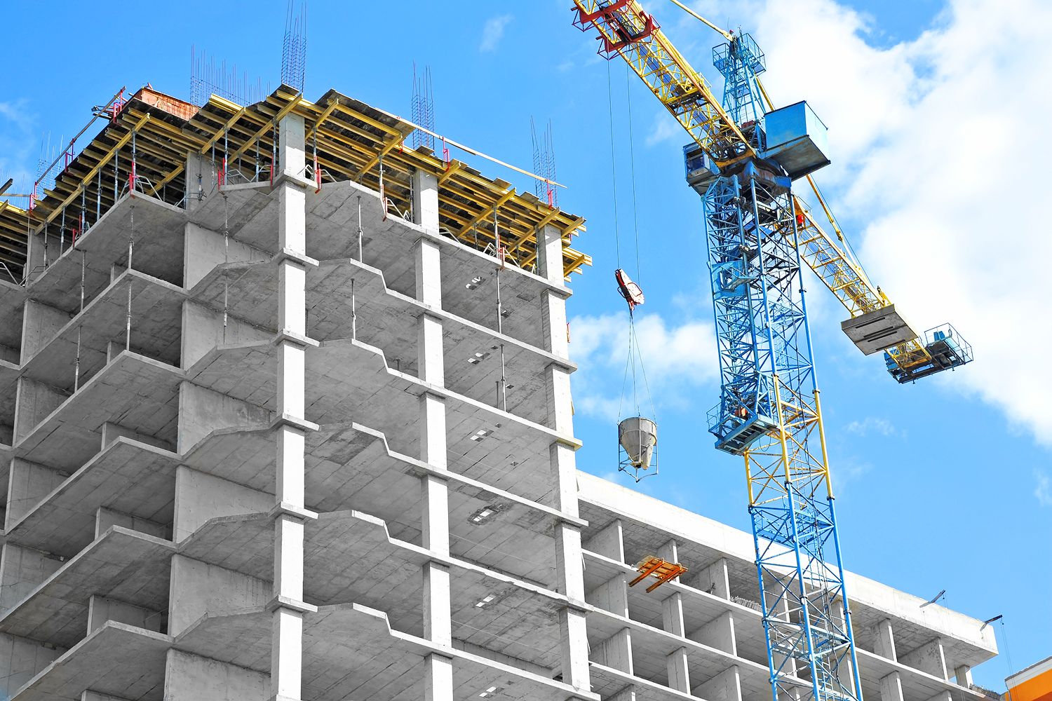 Building construction with crane against blue sky.