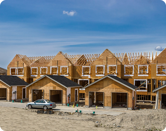 Row of houses under construction with car.