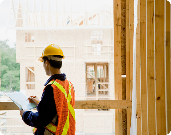 Construction worker reviewing building plans on site.