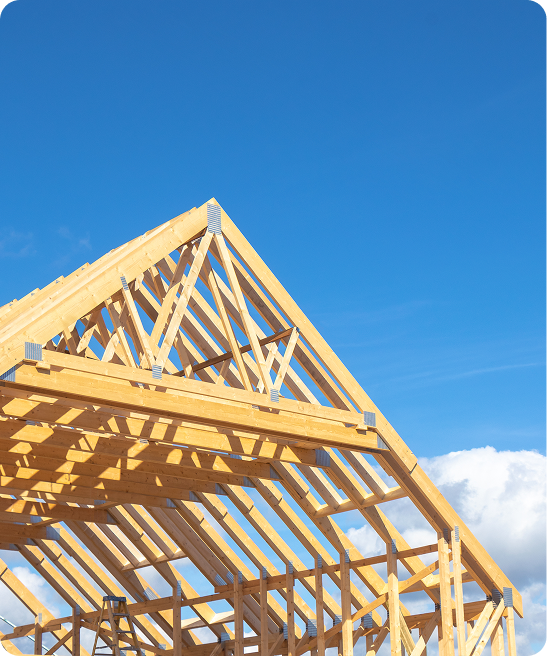 Wooden house frame under clear blue sky.